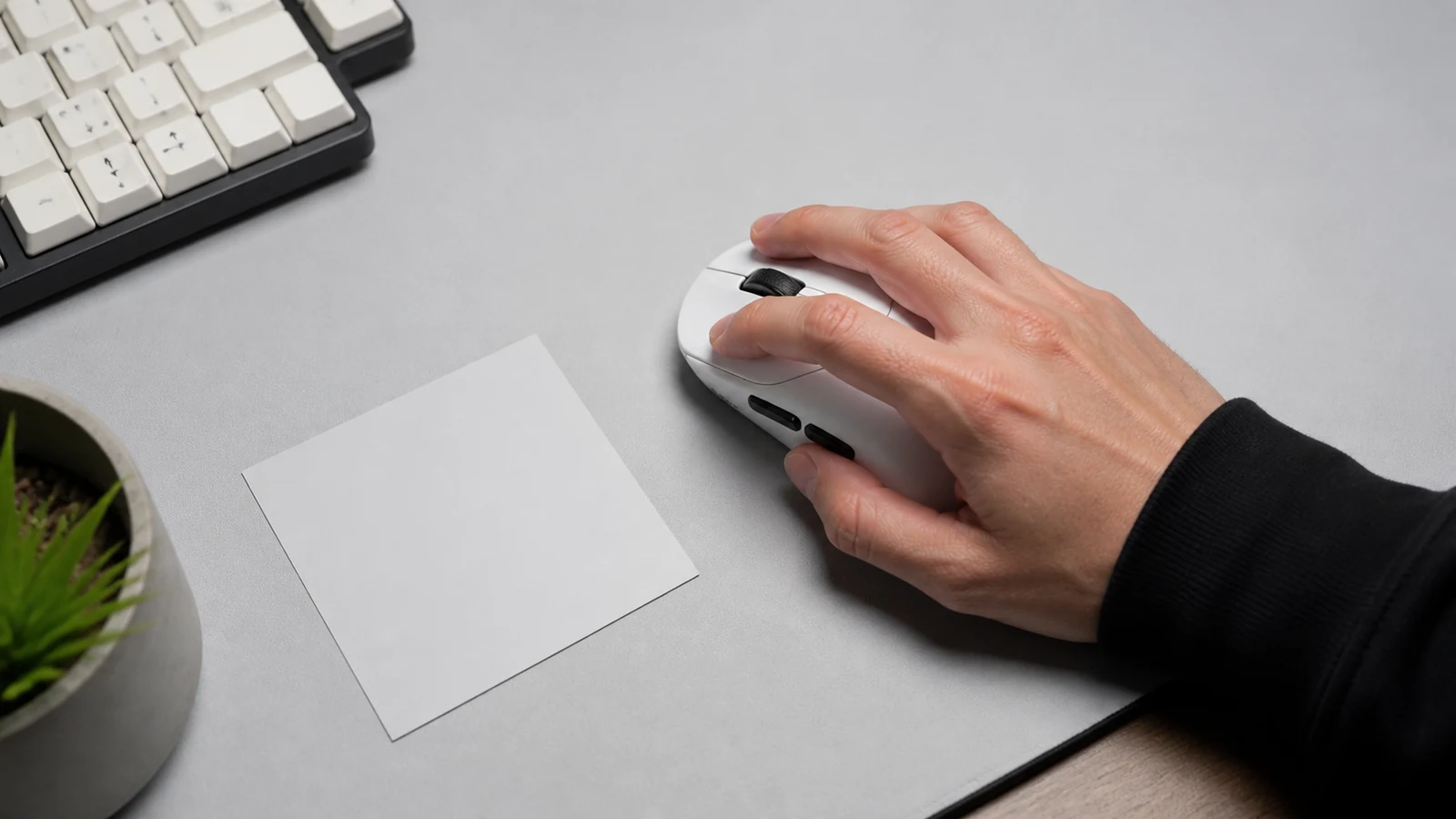 Claw grip hand position over a sub-60g wireless gaming mouse on a UK desk pad